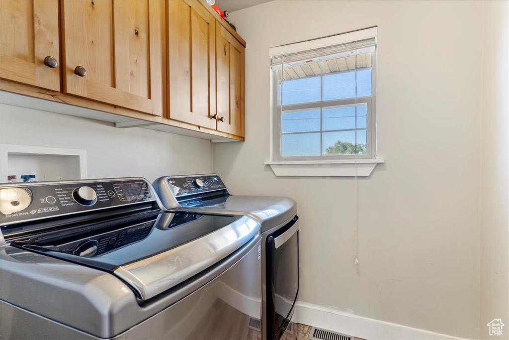 Washroom featuring cabinets, hardwood / wood-style floors, and washer and dryer