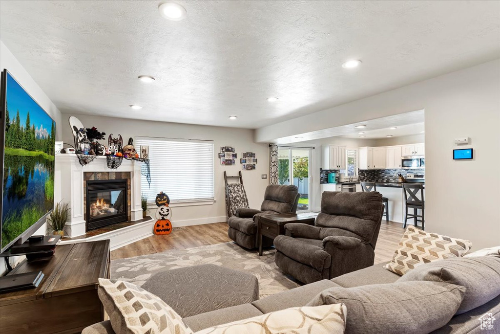 Living room featuring a textured ceiling, light wood-type flooring, and a fireplace