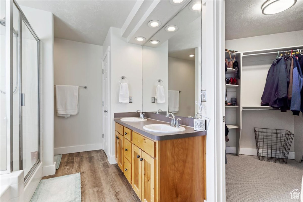 Bathroom with vanity, a shower with shower door, hardwood / wood-style floors, and a textured ceiling