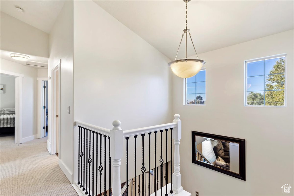 Hall featuring vaulted ceiling and light colored carpet