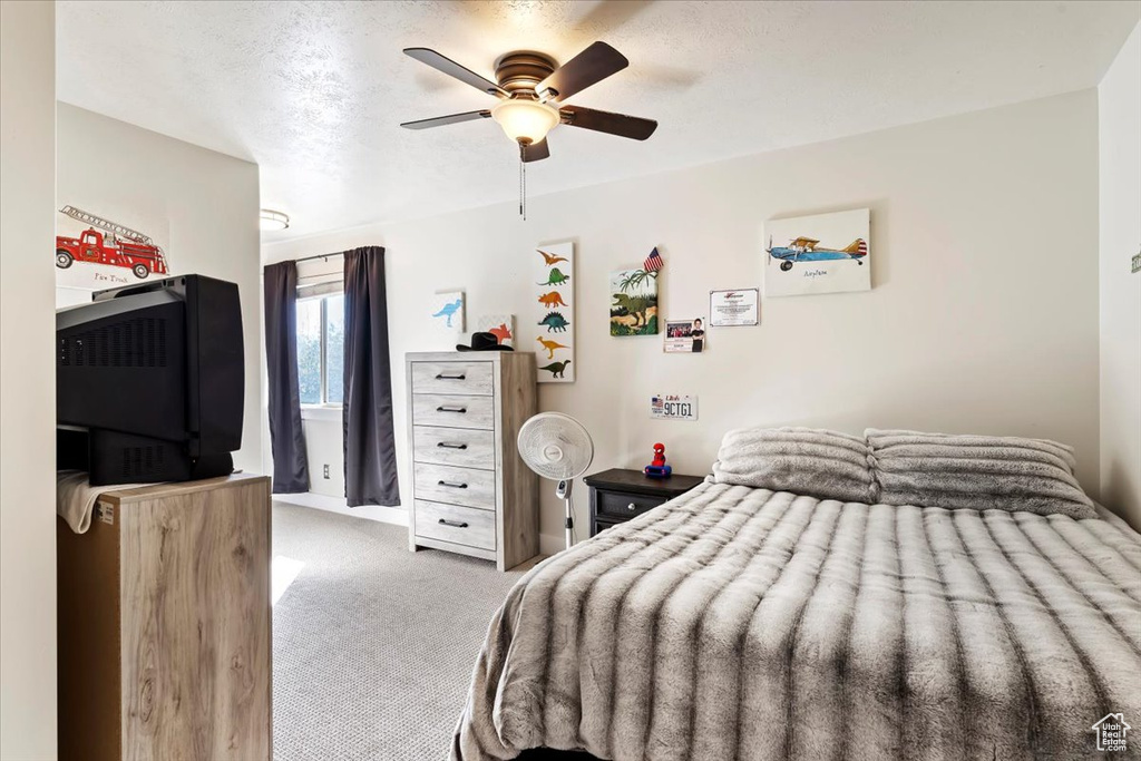 Carpeted bedroom with ceiling fan and a textured ceiling