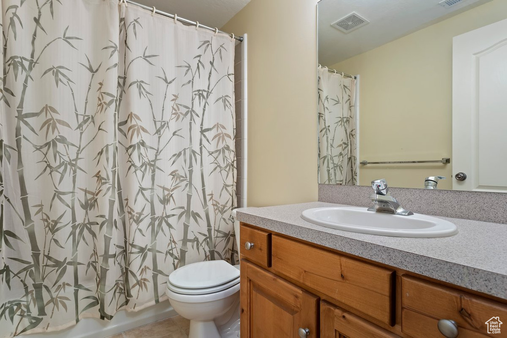 Full bathroom with shower / bath combination with curtain, tile patterned floors, vanity, and toilet