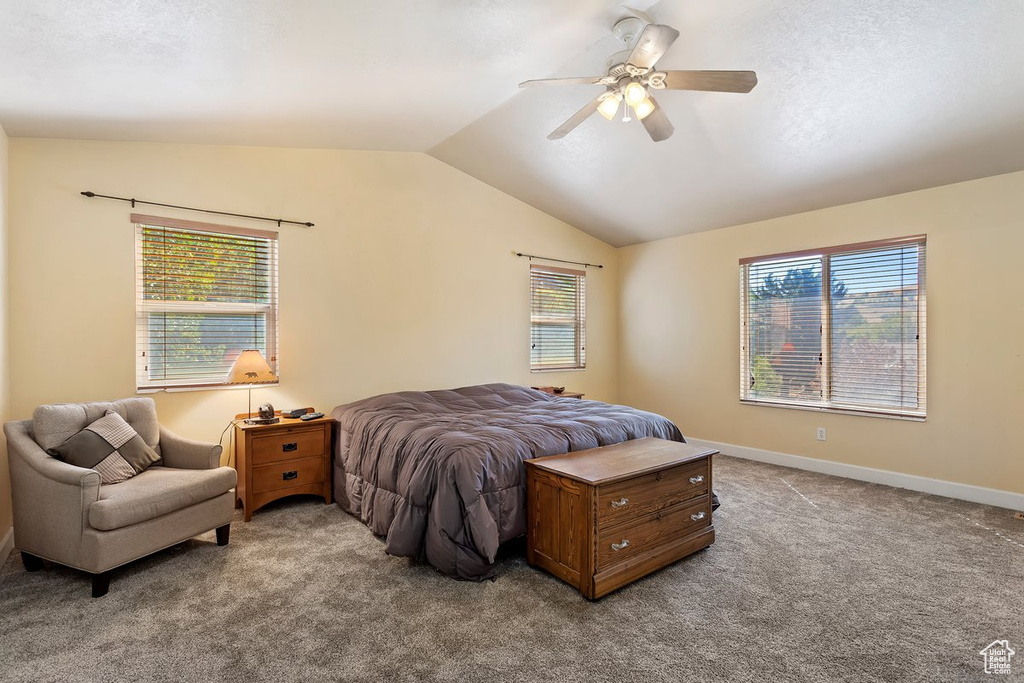 Bedroom featuring multiple windows, vaulted ceiling, ceiling fan, and light colored carpet