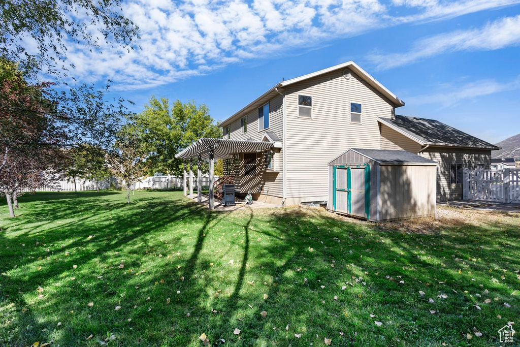 Rear view of house with a shed, a yard, and a patio