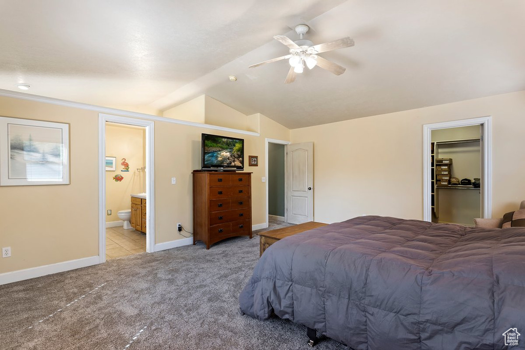 Carpeted bedroom featuring ceiling fan, lofted ceiling, connected bathroom, a walk in closet, and a closet