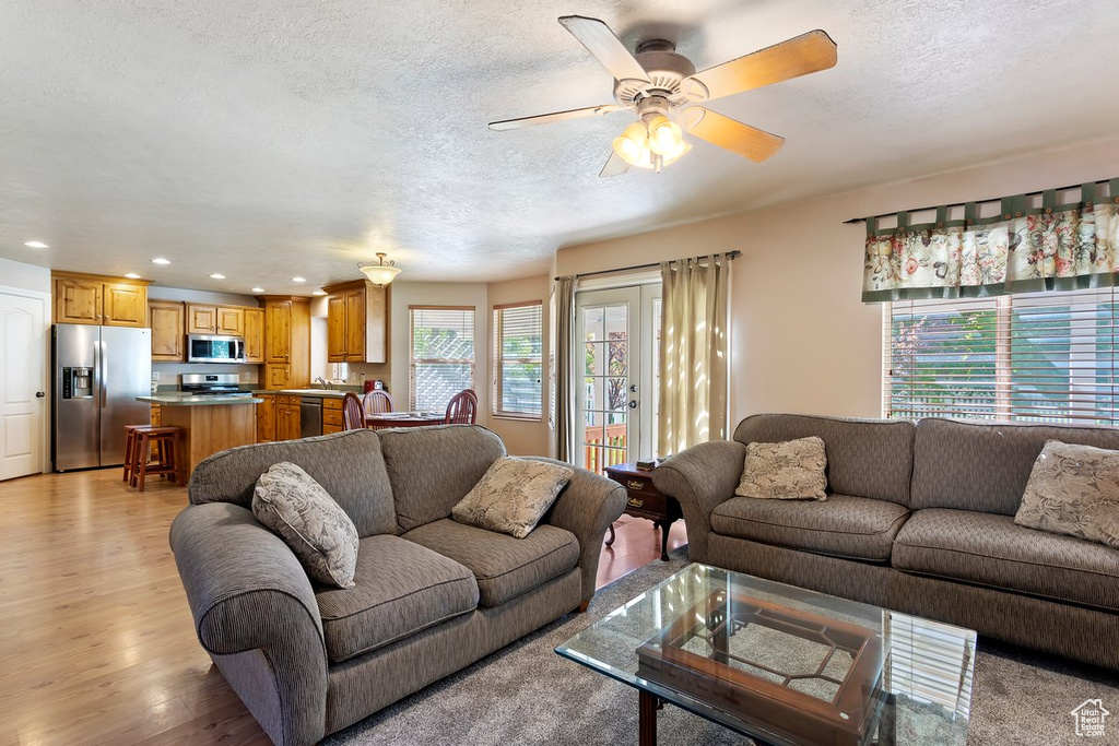 Living room featuring light hardwood / wood-style floors, ceiling fan, and a textured ceiling