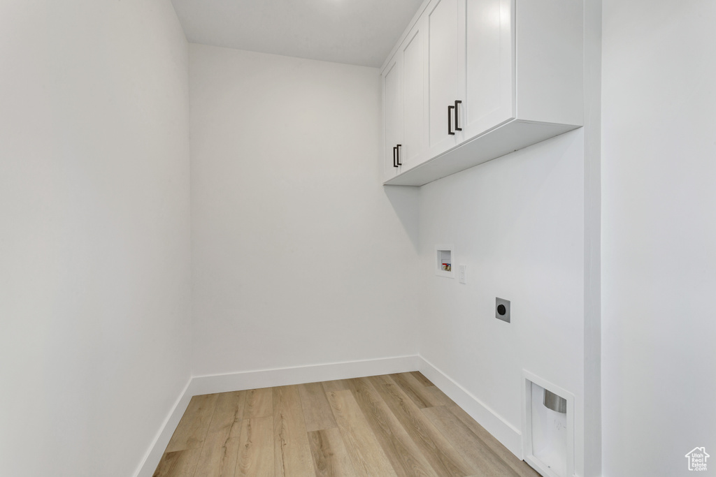 Laundry room featuring cabinets, electric dryer hookup, light hardwood / wood-style flooring, and washer hookup