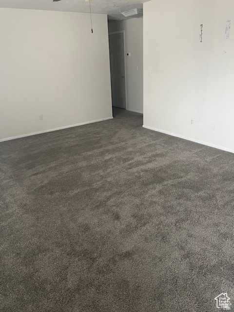 Spare room featuring dark colored carpet and ceiling fan