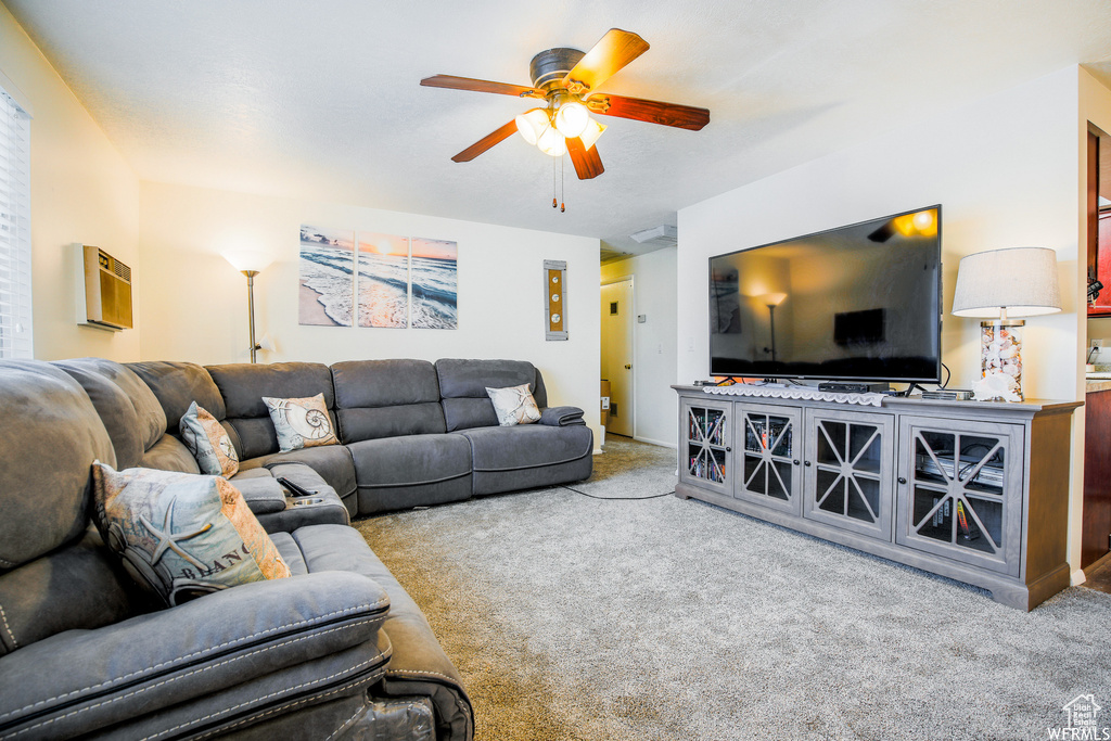 Living room with ceiling fan, carpet flooring, and a wall mounted air conditioner