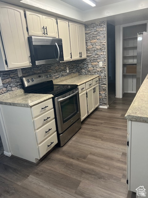 Kitchen featuring backsplash, white cabinetry, dark hardwood / wood-style floors, and stainless steel appliances