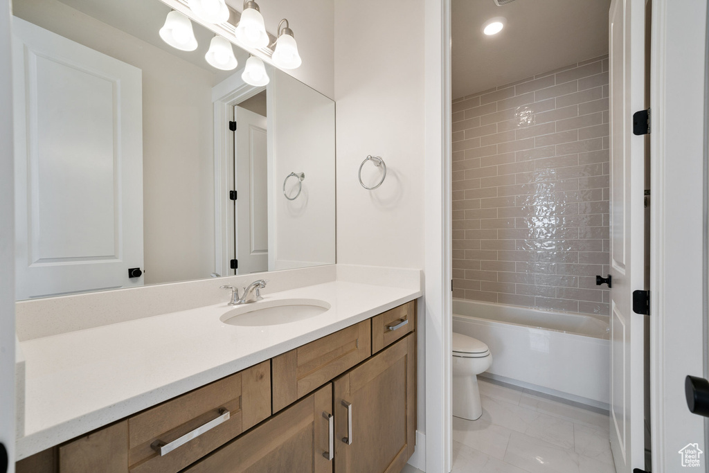 Full bathroom featuring tiled shower / bath combo, vanity, and toilet