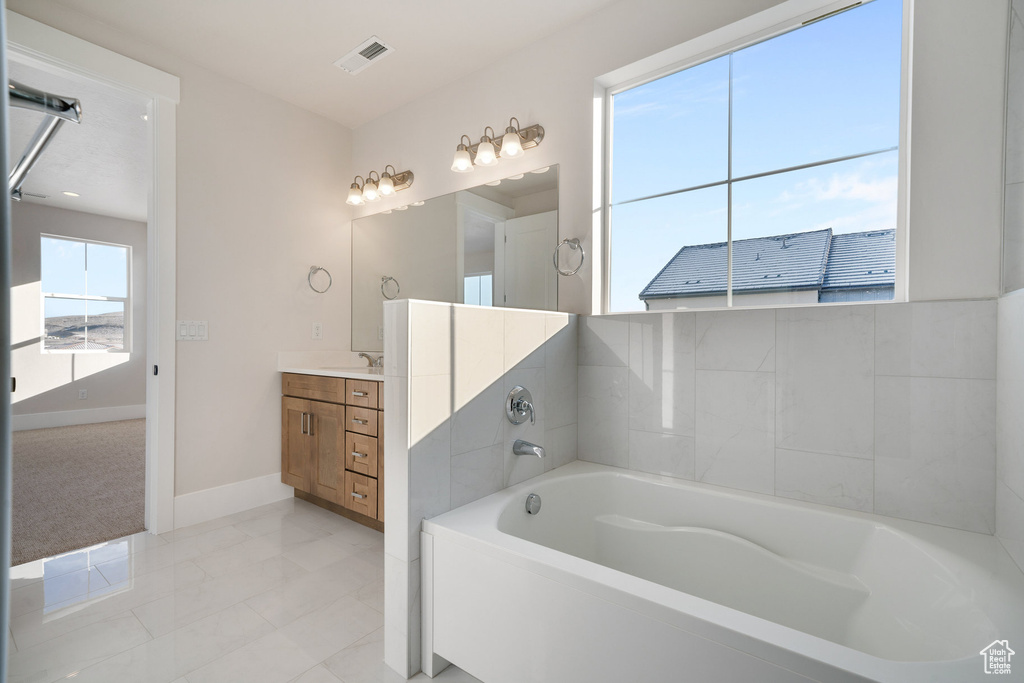 Bathroom featuring a bath, tile patterned flooring, and vanity