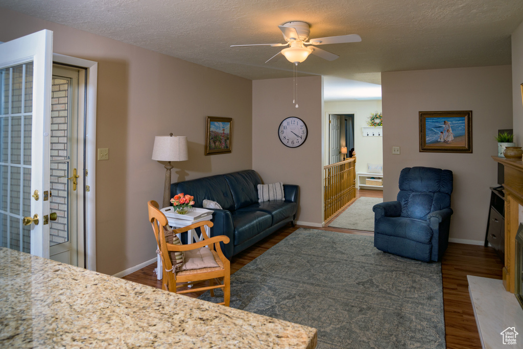 Living room featuring ceiling fan, dark hardwood / wood-style floors, and a textured ceiling