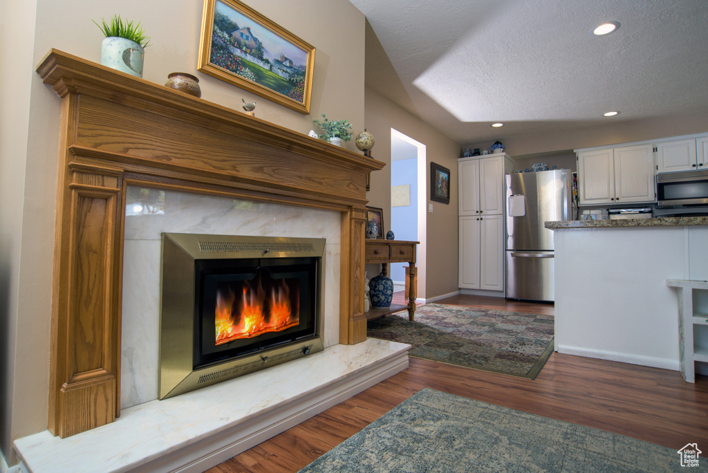 Living room with a textured ceiling, dark hardwood / wood-style floors, and a fireplace