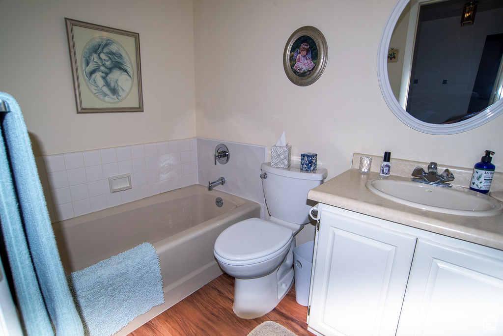 Bathroom featuring vanity, a tub to relax in, hardwood / wood-style floors, and toilet