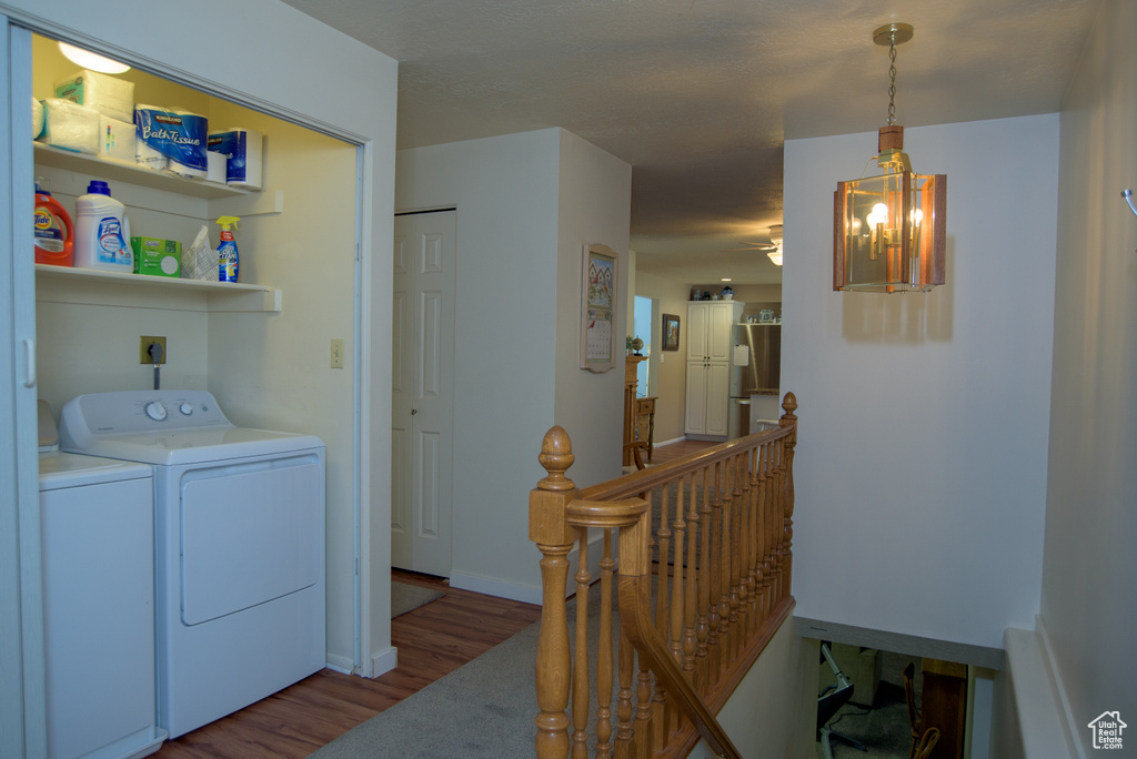 Clothes washing area featuring separate washer and dryer, light hardwood / wood-style flooring, and a chandelier