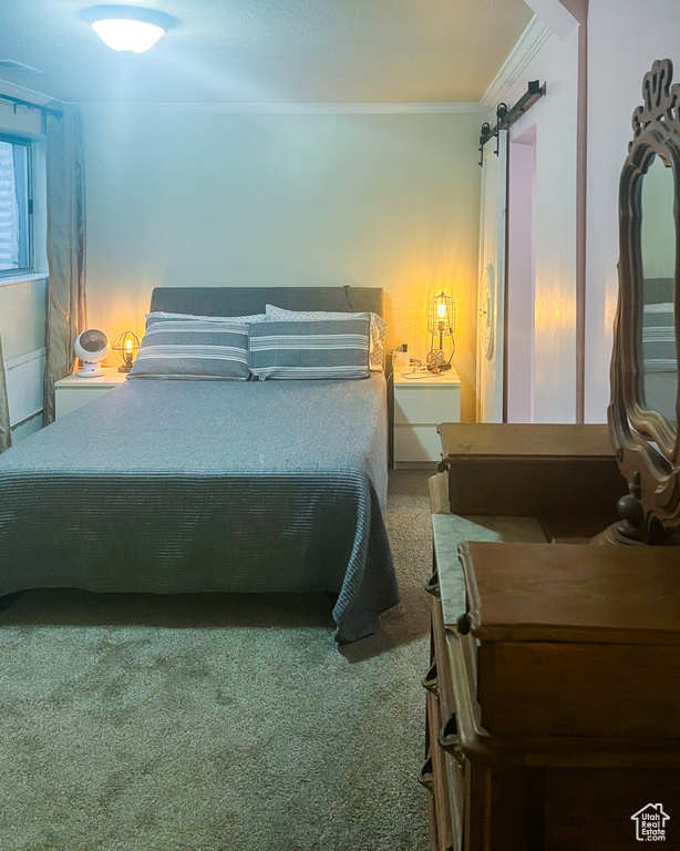 Bedroom featuring ornamental molding, carpet floors, and a barn door