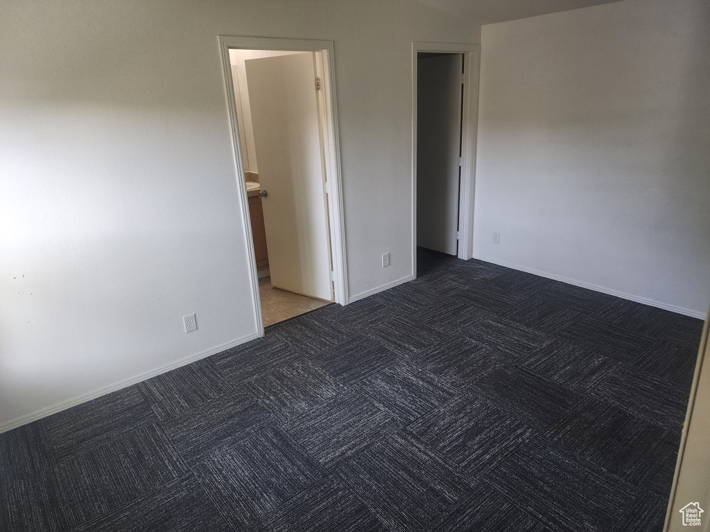 Empty room featuring dark carpet and baseboards