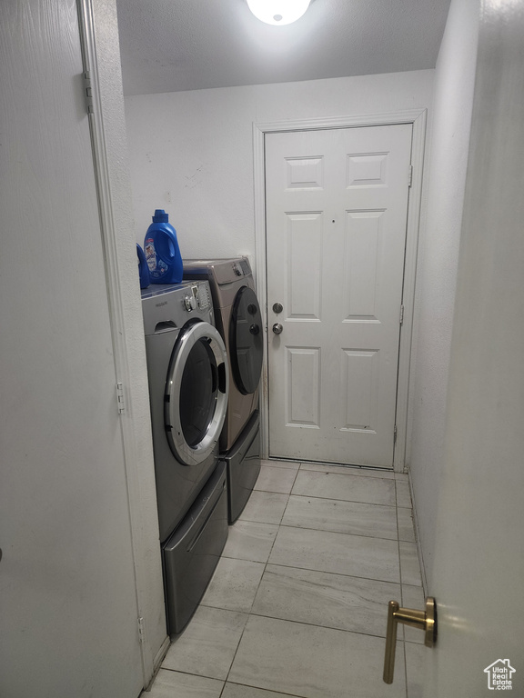 Laundry area with washer and dryer and light tile patterned floors