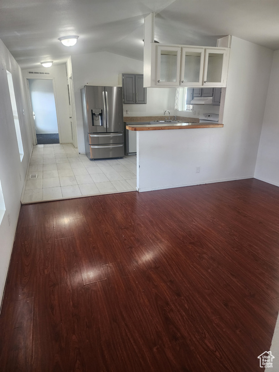 Kitchen with stainless steel fridge with ice dispenser, light wood-style flooring, a peninsula, glass insert cabinets, and a sink