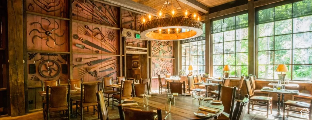 Interior space with wooden ceiling, an inviting chandelier, vaulted ceiling with beams, wooden walls, and hardwood / wood-style floors