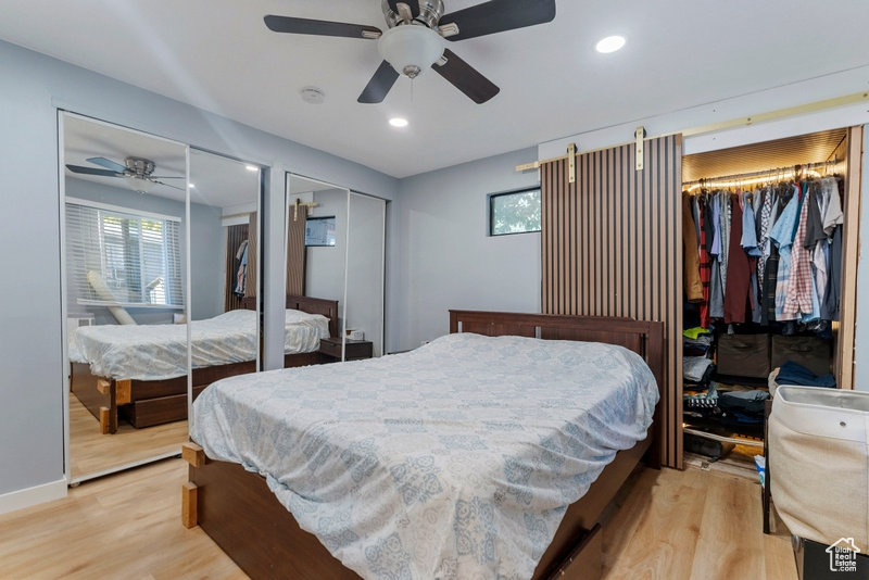 Bedroom featuring ceiling fan, two closets, and light hardwood / wood-style floors