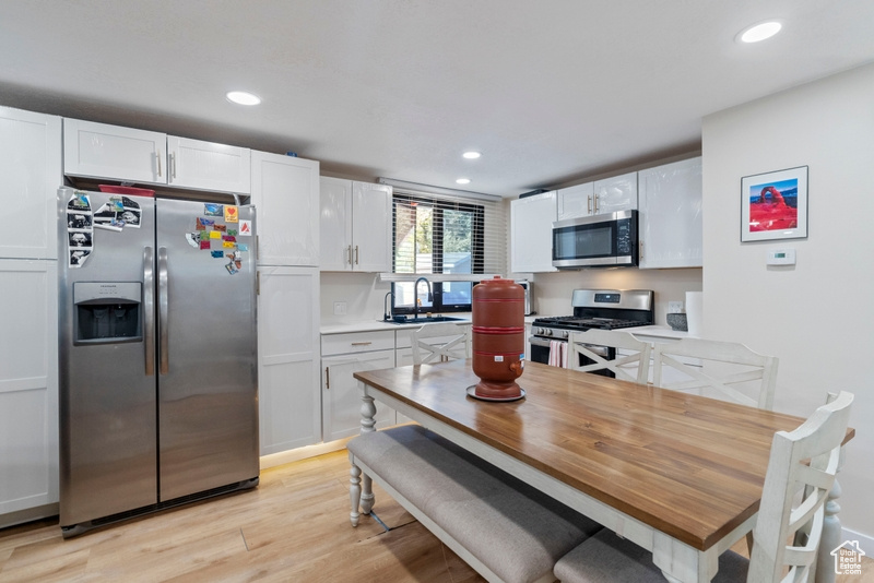 Kitchen featuring white cabinets, light hardwood / wood-style floors, appliances with stainless steel finishes, and sink