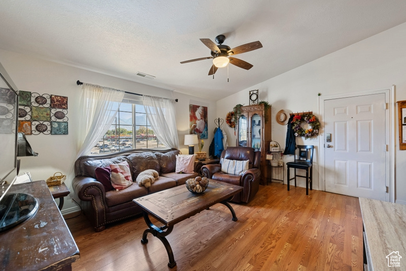 Living room featuring lofted ceiling, ceiling fan, and hardwood / wood-style flooring