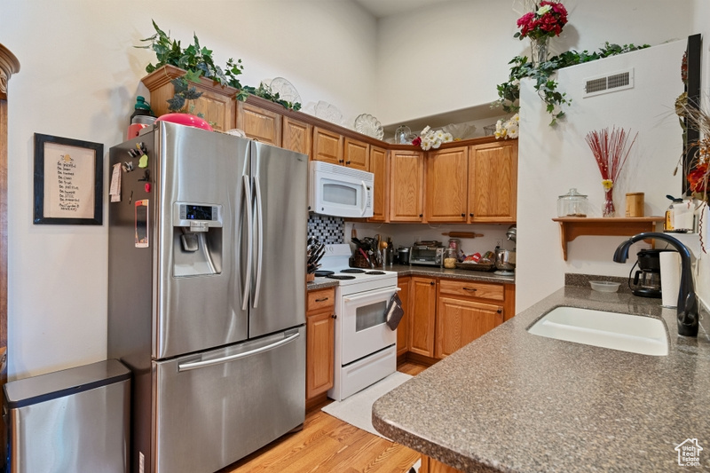 Kitchen with light hardwood / wood-style flooring, sink, and white appliances