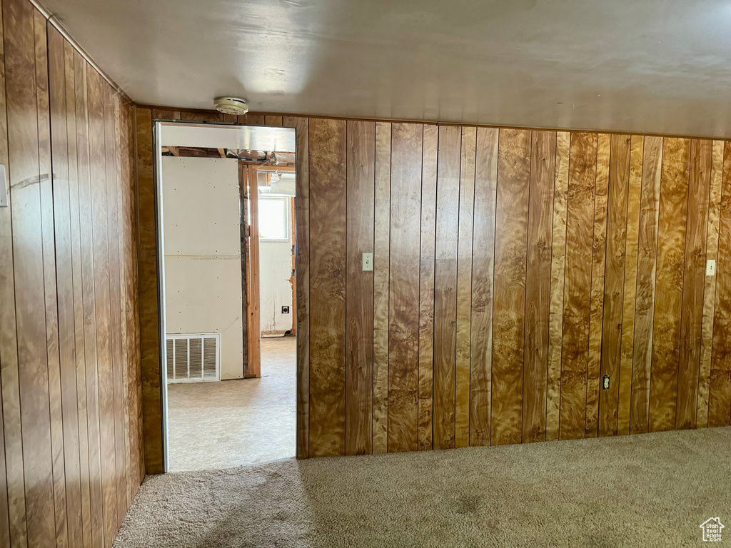 Unfurnished room featuring wooden walls and light colored carpet