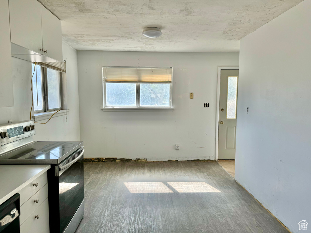 Kitchen with white cabinets, dishwasher, light hardwood / wood-style floors, and stainless steel electric stove