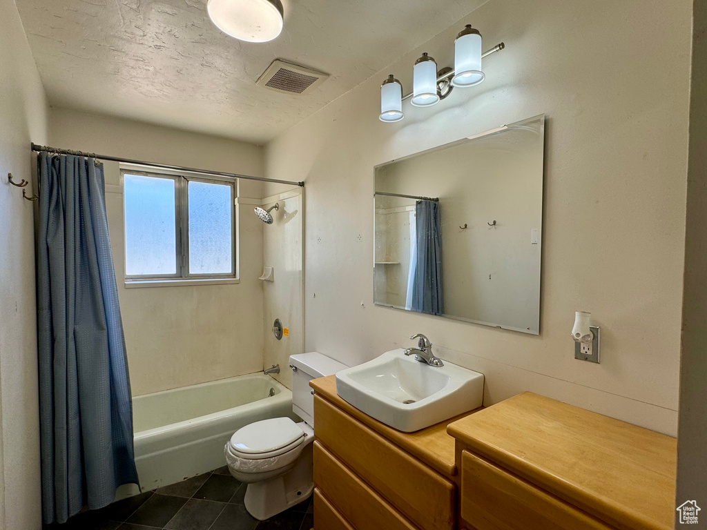 Full bathroom featuring a textured ceiling, shower / bathtub combination with curtain, tile patterned floors, vanity, and toilet