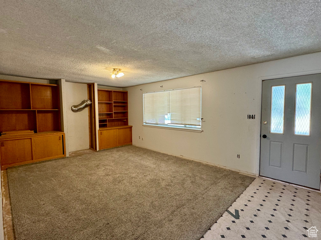 Entrance foyer featuring light carpet and a textured ceiling