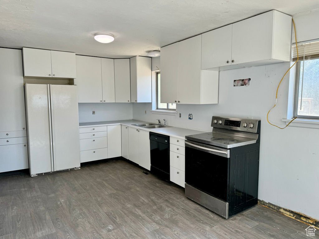 Kitchen with white cabinetry, dark wood-type flooring, white refrigerator, stainless steel range with electric stovetop, and dishwasher