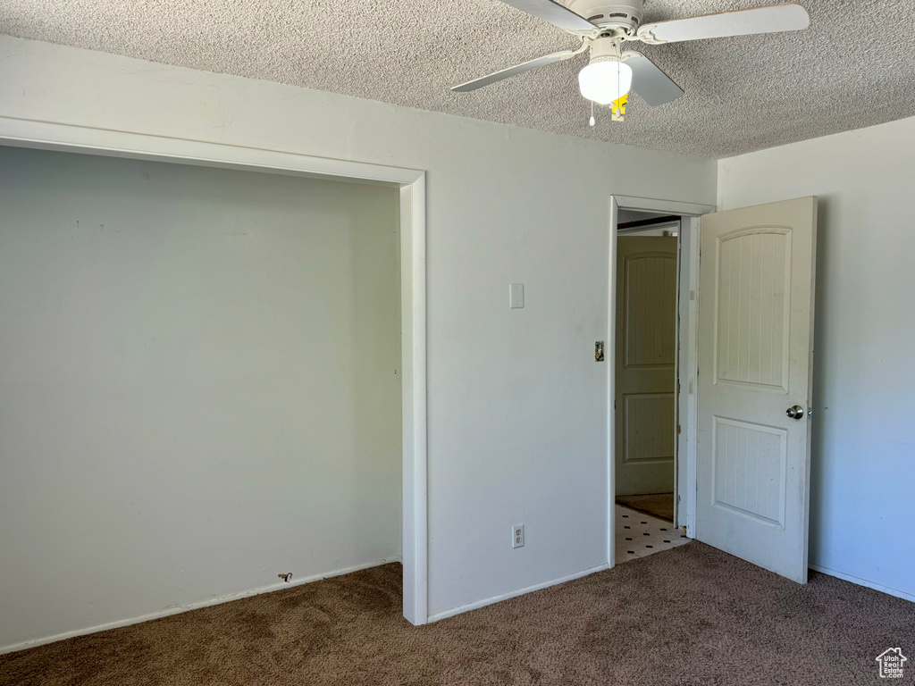 Interior space featuring a textured ceiling, carpet, ceiling fan, and a closet