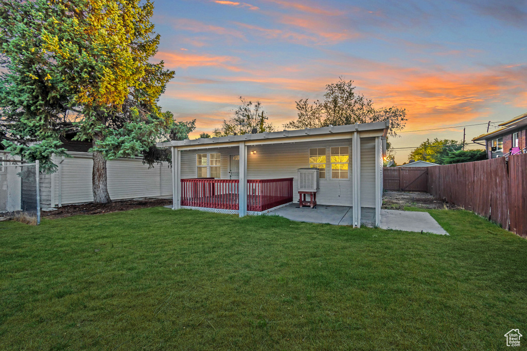 Back house at dusk with a patio and a yard