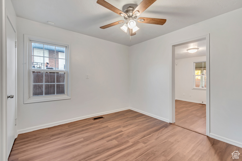 Empty room with ceiling fan and light wood-type flooring