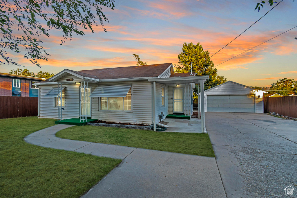 View of front facade with a yard, an outdoor structure, and a garage