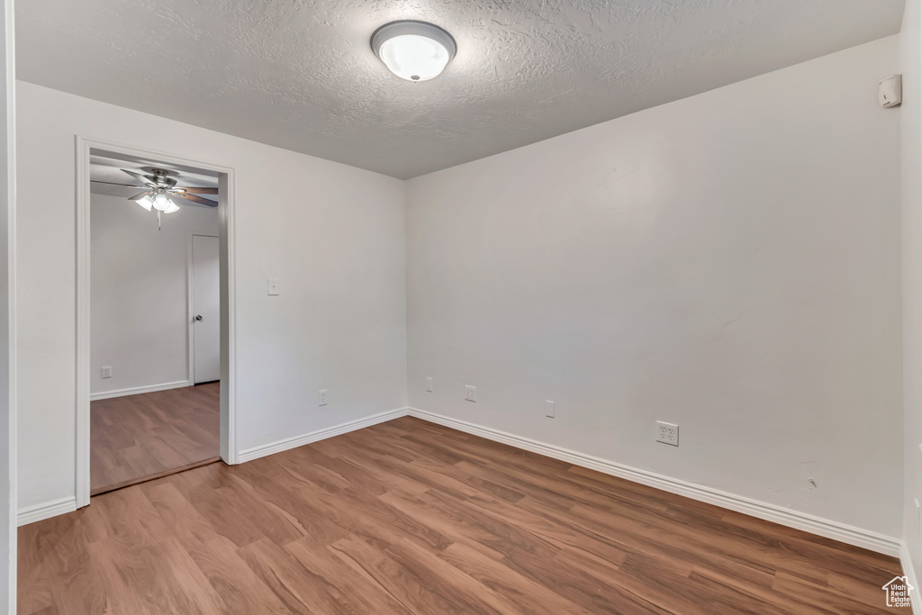 Empty room with ceiling fan, a textured ceiling, and light hardwood / wood-style flooring