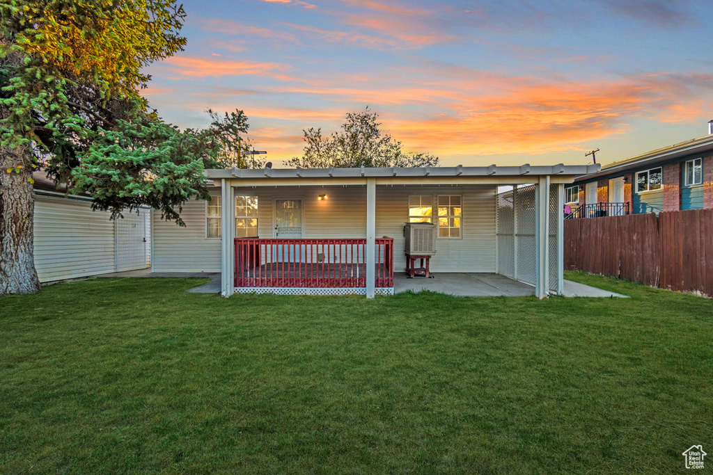 Back house at dusk featuring a porch and a yard