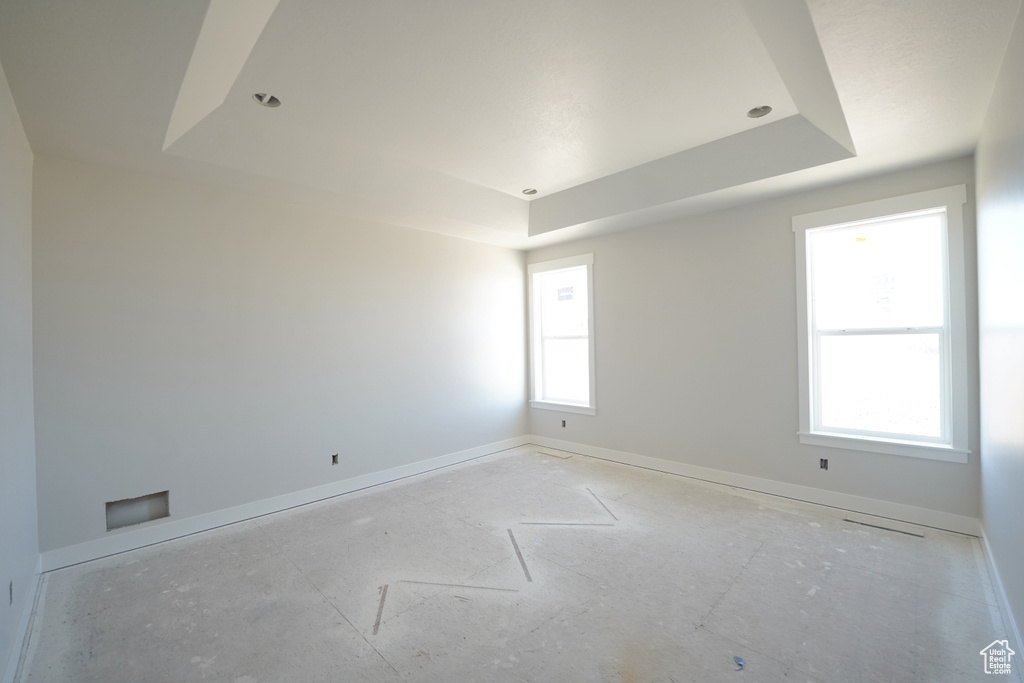 Unfurnished room with a raised ceiling and plenty of natural light