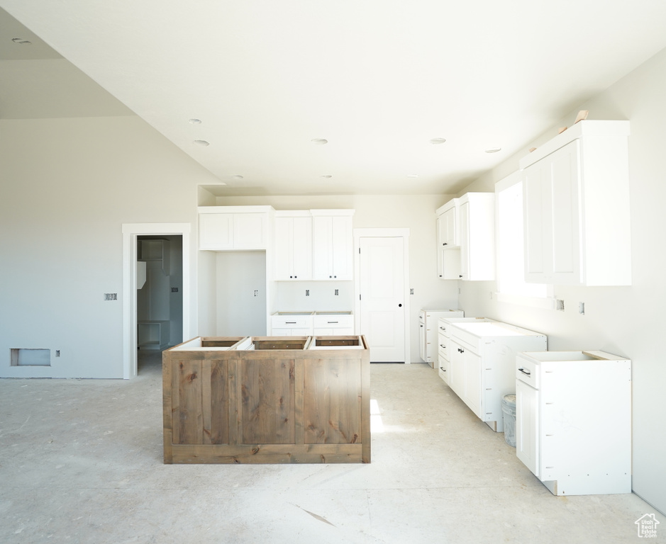 Kitchen featuring washer / clothes dryer, a center island, and white cabinets