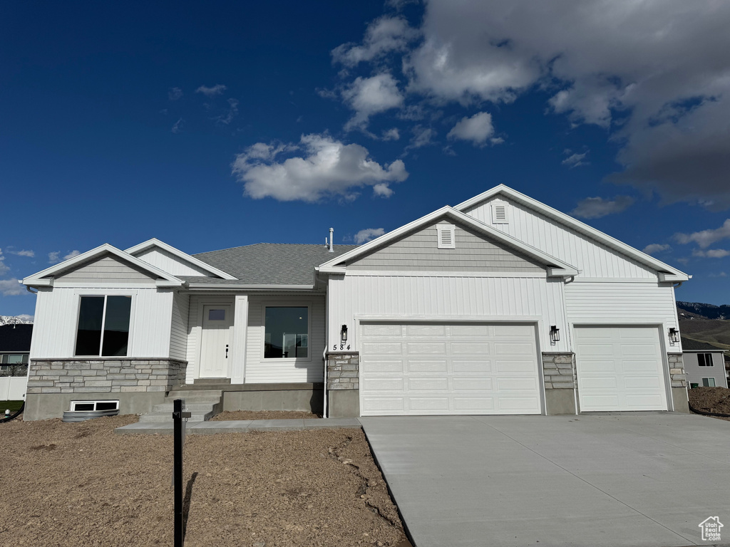 View of front of property featuring a garage, driveway, and stone siding