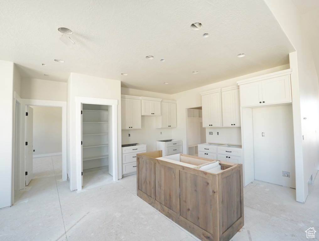 Kitchen featuring white cabinets, a textured ceiling, and a center island