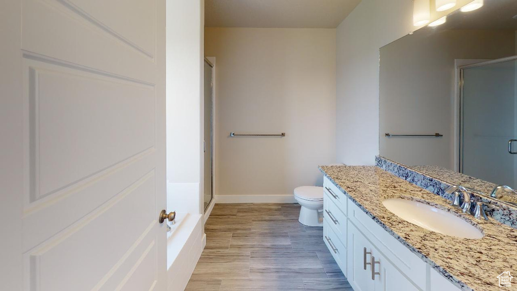 Bathroom with hardwood / wood-style flooring, vanity, toilet, and a shower with shower door