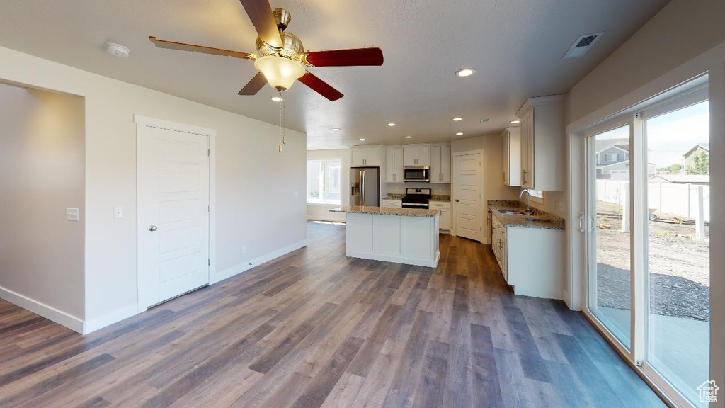 Kitchen with white cabinets, a kitchen island, dark hardwood / wood-style flooring, stainless steel appliances, and sink