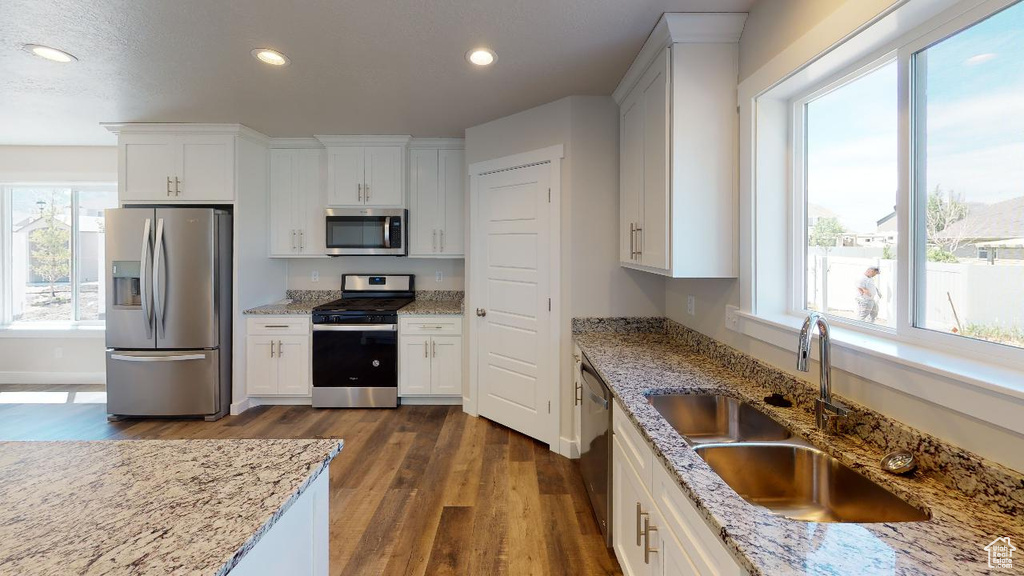 Kitchen with appliances with stainless steel finishes, plenty of natural light, sink, and white cabinetry