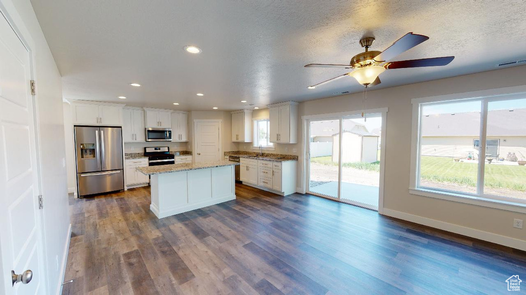 Kitchen with appliances with stainless steel finishes, white cabinets, a kitchen island, dark hardwood / wood-style floors, and sink