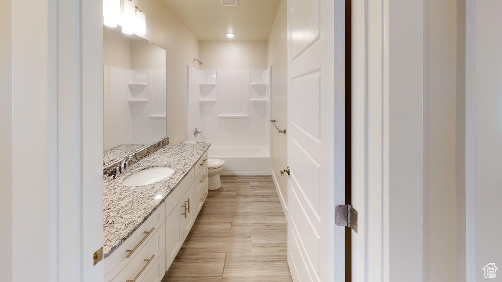 Full bathroom featuring vanity, shower / bath combination, toilet, and hardwood / wood-style flooring