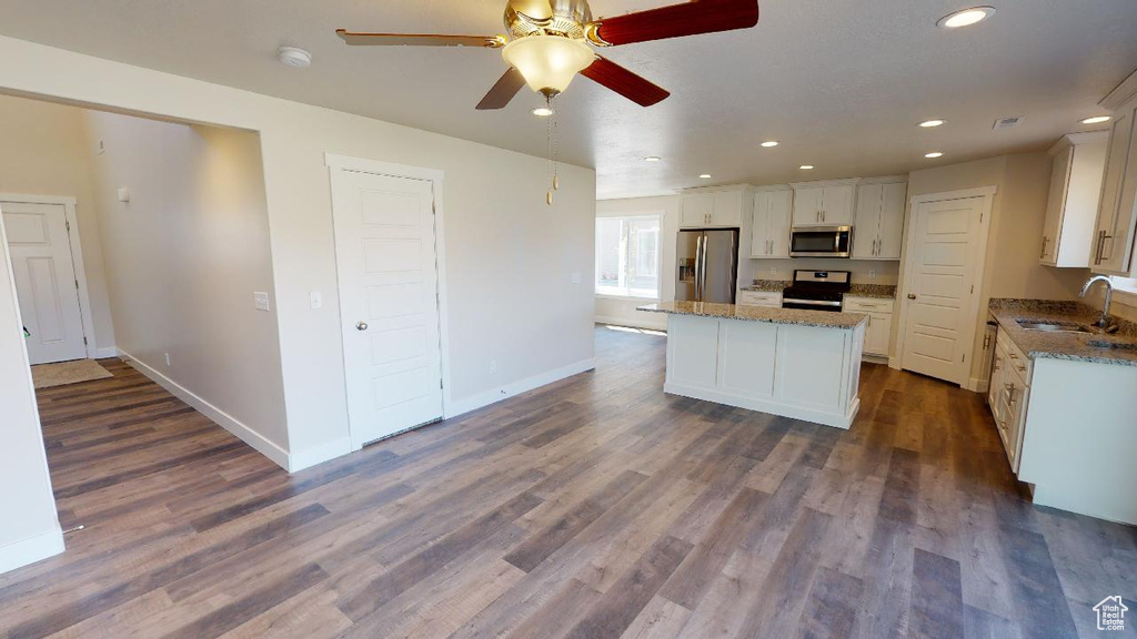 Kitchen featuring sink, white cabinets, a kitchen island, stainless steel appliances, and dark hardwood / wood-style flooring